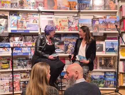 Two people talking in front of a book shelf